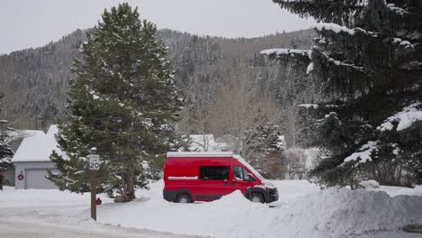 parked red van in village and white snowy mountain landscape on cold winter day