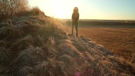woman contemplating sunrise/sunset over a golden field