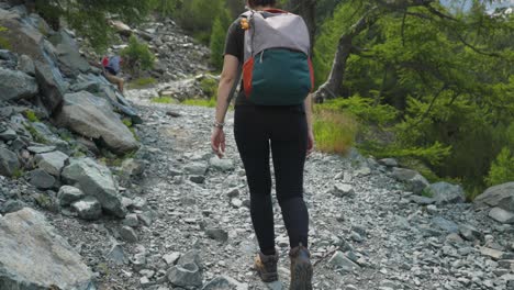 una chica mochila caminando por un sendero de montaña en el alpe ventina, italia - ancho
