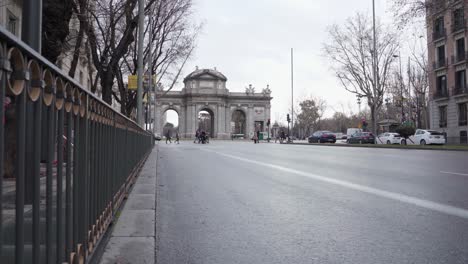 scene on the road in madrid, spain with the famous puerta de alcala, a neo-classical gate in the plaza de la independencia, in the background - sideways long shot