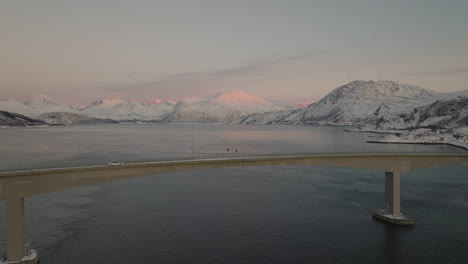 drone shot flying over sommaroy bridge in norway with mountains and ocean