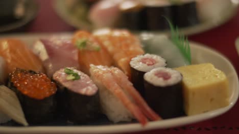 Platten-Mit-Köstlichen-Sushi-Sorten,-Serviert-In-Einem-Sushi-Restaurant-In-Tokio,-Japan-–-Nahaufnahme,-Kamerafahrt