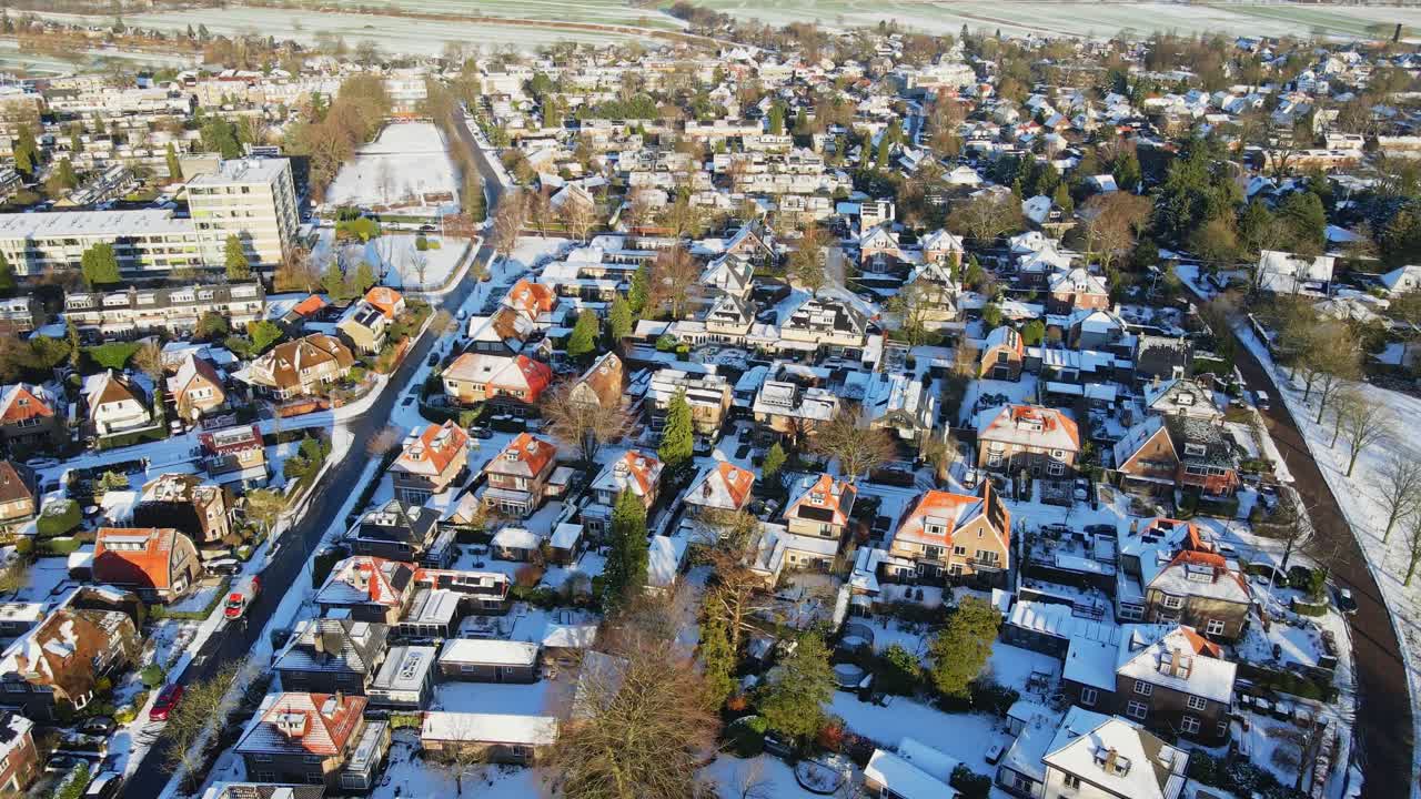 Luftfoto af et smukt, velhavende kvarter dækket af sne på en solrig vinterdag