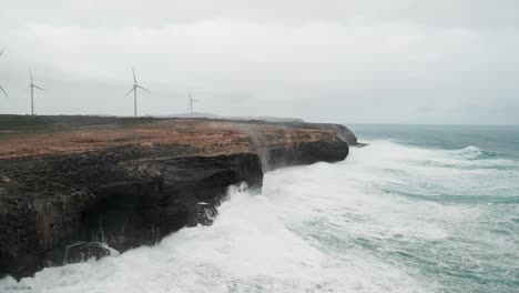 Panning-drone-view-of-ocean-water-hitting-the-coast-of-Cape-Bridgewater,-Australia-under-a-cloudy-day