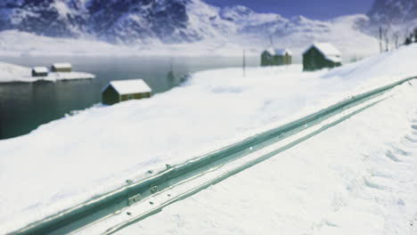 snowy landscape near a tranquil lake with distant cabins and mountains