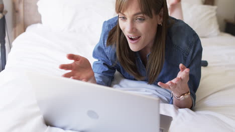 middle-aged caucasian woman enjoys a relaxed moment on her bed at home