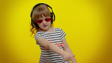 cheerful cute blonde child kid listening music via headphones dancing disco fooling having fun party