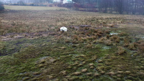 flying towards boat strandad in wetland next to lake, scandinavia nature, aerial view