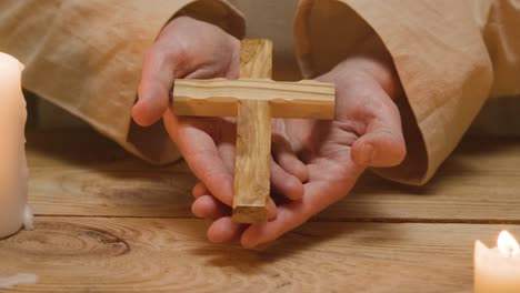 close up shot of man wearing robes representing figure of jesus christ holding wooden cross 1