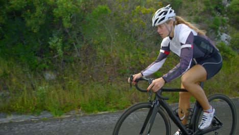 female cyclist cycling on a countryside road 4k