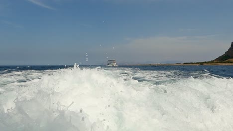 Low-Winkel-Wasseroberfläche-Pov-Des-Bootsspurwegs-Mit-Riserva-Dello-Zingaro-Naturschutzgebiet-Von-Sizilien-Im-Hintergrund