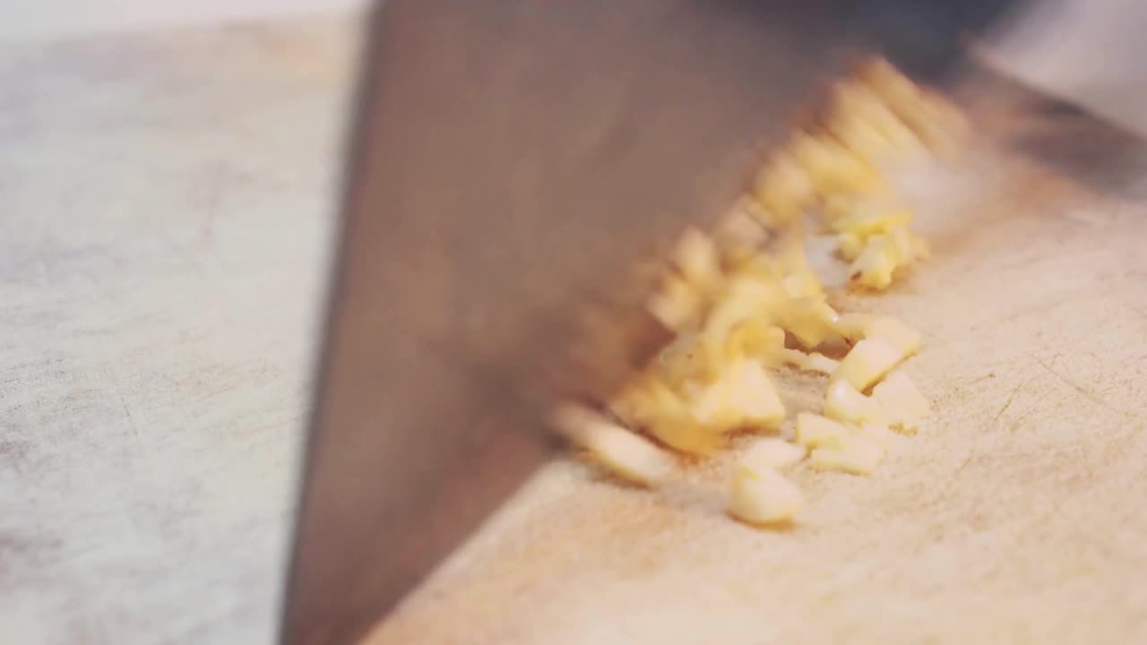 A chef slices garlic on chopping board close up