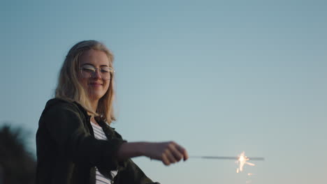young-woman-dancing-with-sparklers-on-beach-at-sunset-celebrating-new-years-eve-having-fun-independence-day-celebration-with-fireworks-enjoying-freedom