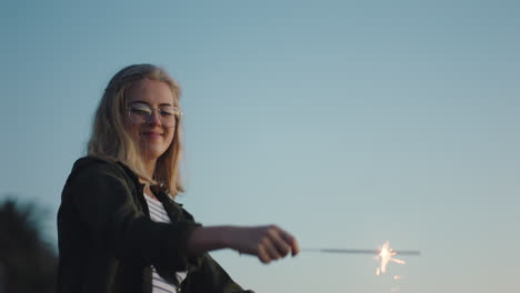 mujer joven bailando con bengalas en la playa al atardecer celebrando la víspera de año nuevo divirtiéndose celebración del día de la independencia con fuegos artificiales disfrutando de la libertad