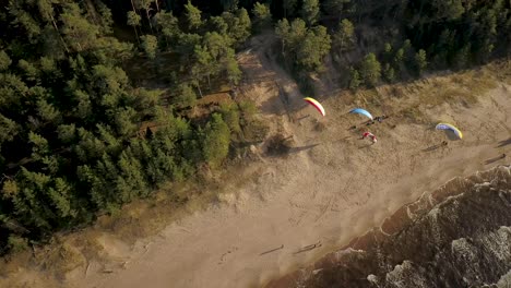 Aerial-shot-of-paragliders-gliding-at-low-altitude-above-Saulkrasti-beach-in-Latvia