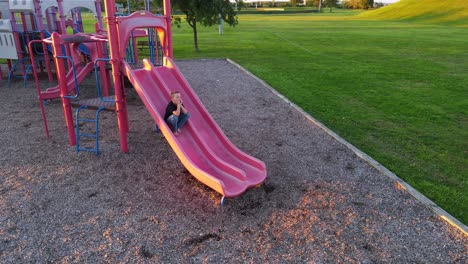happy child climbing slide backwards and stops, aerial orbit view