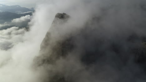 low clouds covering majestic mountain peaks in dolomites, italy - aerial view