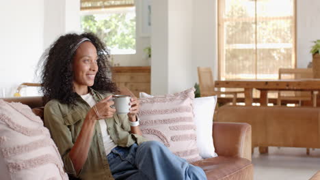 relaxing at home, woman enjoying coffee on sofa, looking thoughtful and content