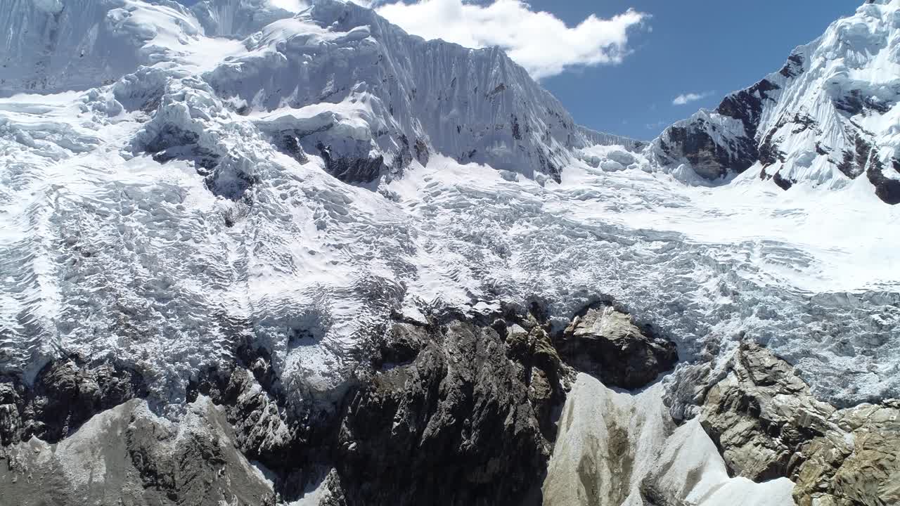 A breathtaking aerial view of a glacier cascading down rugged mountains