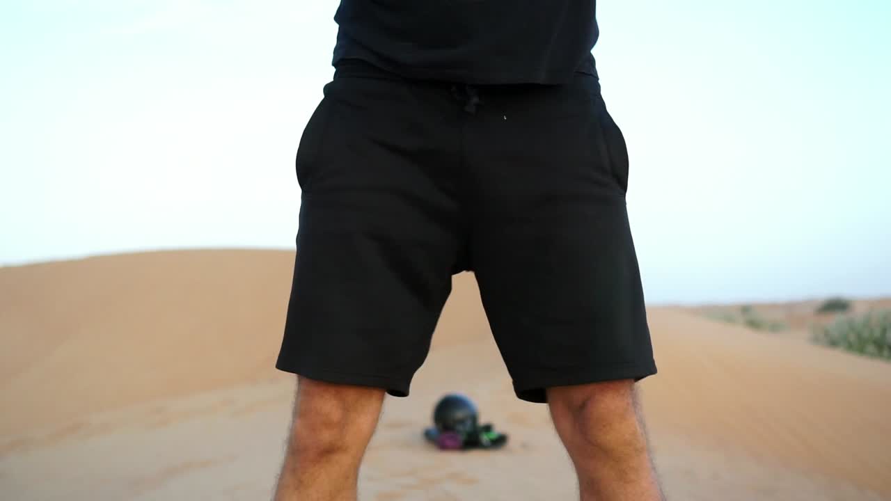 Sporty Man does cross fit exercise kettlebell swing with squats in desert, filmed close up