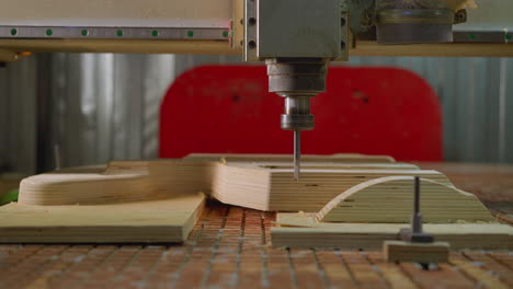 cnc machine in operation, detailed close-up of drill bit carving a pattern on plywood in a workshop