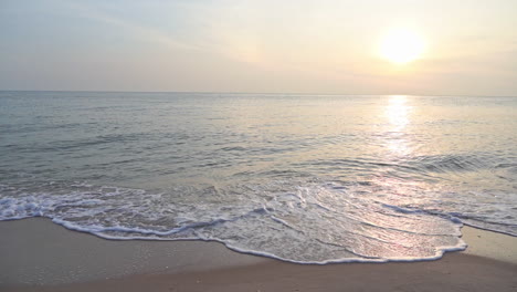 colorful sunset over the calm sea with crashing waves on sand beach