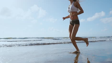 fitness runner woman running on beach listening to music motivation with phone case sport armband strap. sporty athlete training cardio barefoot with determination under summer sun.