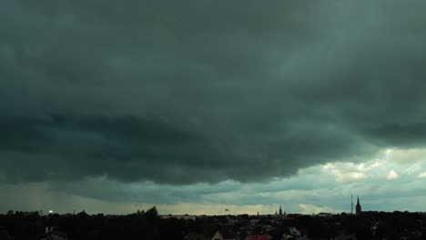 Time-lapse-of-dark-dramatic-fast-moving-storm-clouds-over-the-city,-medium-shot