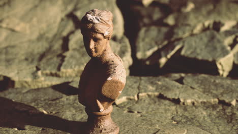 bust of a classical figure on textured stone softly illuminated