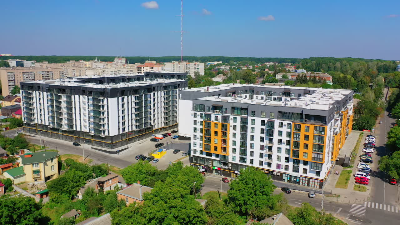 Modern residential complex in the city. Newly built apartment buildings in sunny daytime. Exterior of new urban infrastructure. Aerial view. Motion camera back.