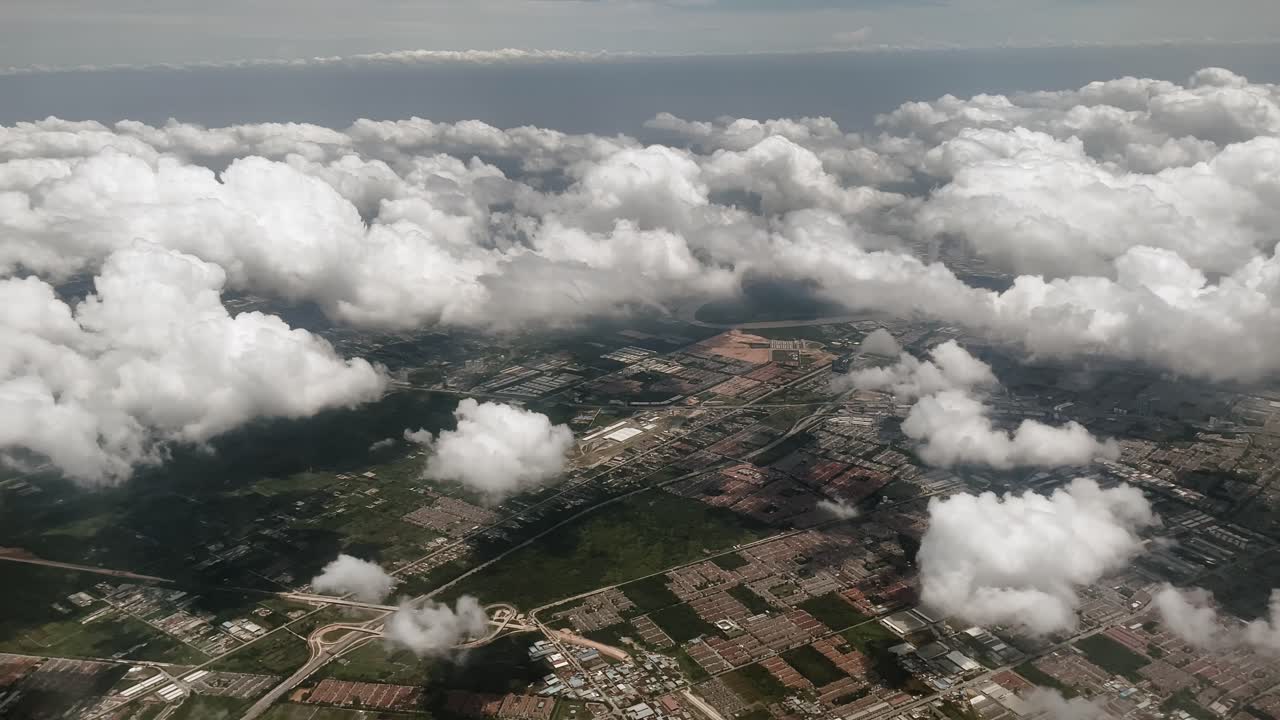 Bird's-eye view from an airplane above a serene island and clouds, capturing the flight's mesmerizing journey through the cloud cover