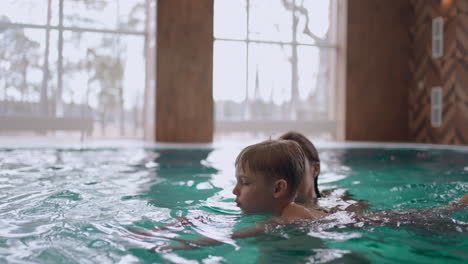 mother-is-teaching-his-little-son-to-swim-in-pool-indoor-swimming-pool-in-wellness-center