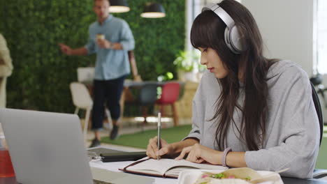 Headphones,-laptop-and-notebook-writing-for-woman