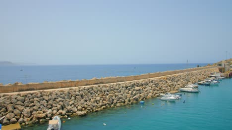 Kleine-Boote,-Die-Im-Sonnenlicht-An-Der-Ufermauer-Im-Meer-Festgemacht-Sind