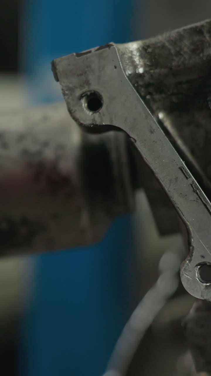 ingeniero con guantes rojos opera una herramienta neumática en el bloque del motor en un taller industrial, close-up captura el proceso de reparación mecánica, y componentes metálicos con vehículo blanco borroso en el fondo