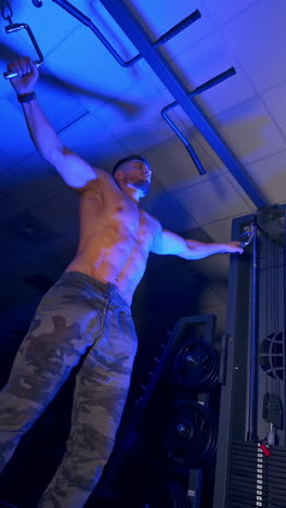 Athlete with strong body doing work out pushing up excercise in gym. View from the bottom. Blue light filter. Vertical video