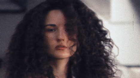 portrait of beautiful girl with curly hair standing under concrete bridge