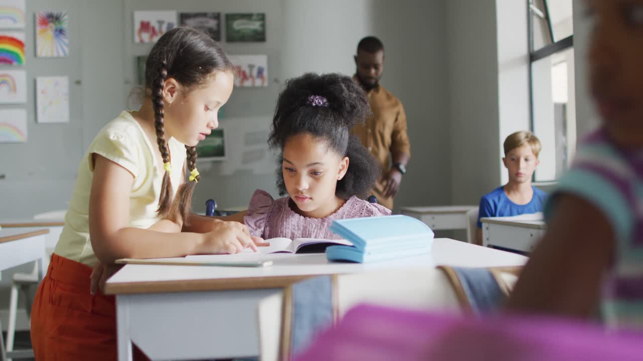 Video of diverse girls at desk doing lessons together in classroom
