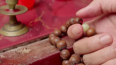 person hand touching rosary prayer beads inside spiritual place