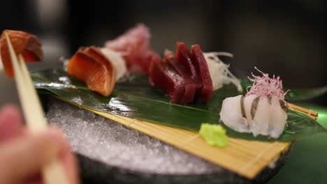 person picks up sushi pieces with chopsticks