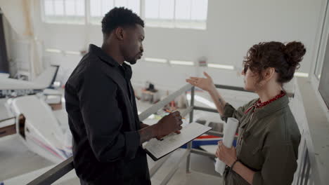 two avionics technicians discussing planes in aircraft hangar