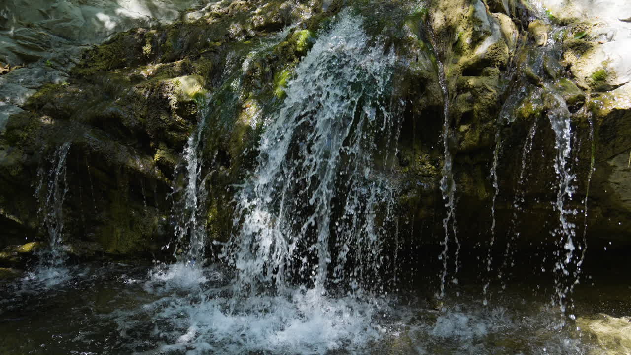 Descending shot of small waterfall running into creek below located in Santa Paula Punch Bowls Southern California