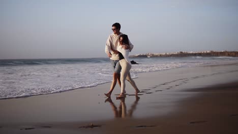 Couple-romantic-walk-on-beach,-lovers-walking-barefoot-on-sand.-Summer,-couple-in-love,-an-exotic-vacation,-wind-waving-female-hair,-background-sand-and-water,-sunny-weather