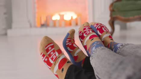un par de pies en acogedores calcetines navideños cerca de la chimenea 1