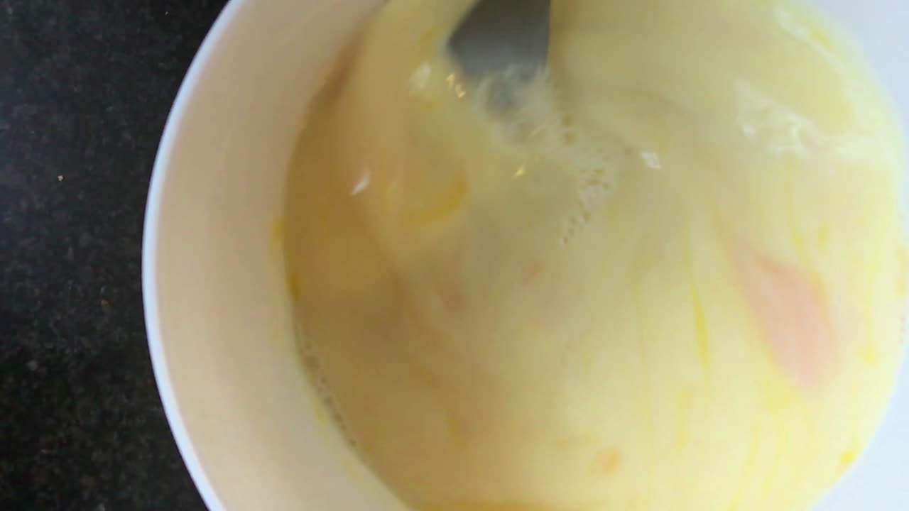 revolviendo los huevos para un desayuno en un tazón blanco