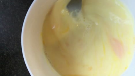 stirring eggs for a breakfast in a white bowl