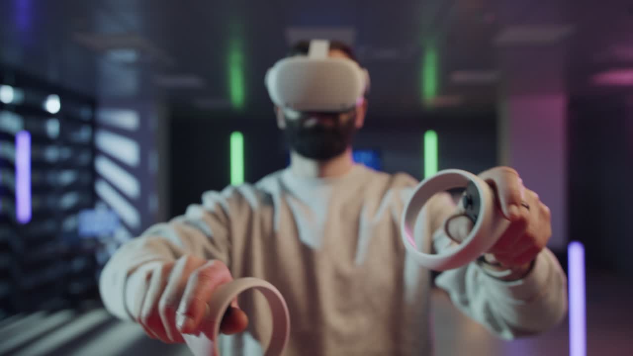A man wears a virtual reality headset and actively uses two controllers to interact with a digital world. The futuristic, neon-lit environment enhances the theme of immersive gaming and the metaverse.