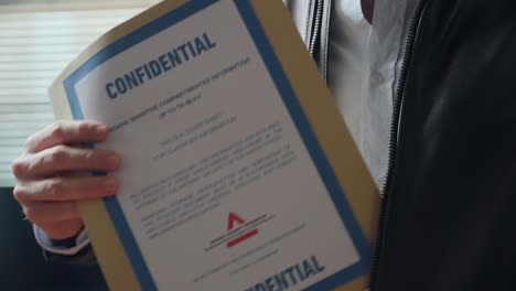 spy or agent taking out secret confidential envelope with classified documents from his jacket in office setting. mysterious person revealing stolen file folder with sensitive government information