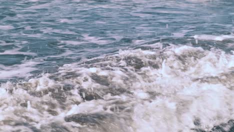 movimiento lento de burbujas espumantes olas del océano en la costa de la isla de bali en indonesia en el sol. dos olas chocan chocando entre sí creando salpicaduras del océano índico. 4k