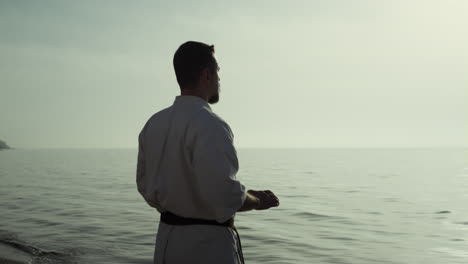 karate fighter perfecting martial technique at sunset. man practicing taekwondo.